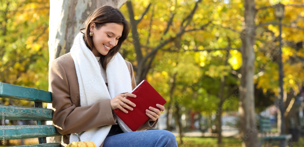 Obraz premium Mindfulness and mental health, young woman reading a book on a park bench during autumn for relaxation and personal growth in a peaceful outdoor setting