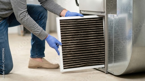 Person replacing a dirty hvac air filter in a home furnace