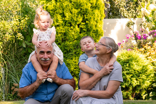 Grandchildren Riding and Hugging Grandparents in Sunny Garden