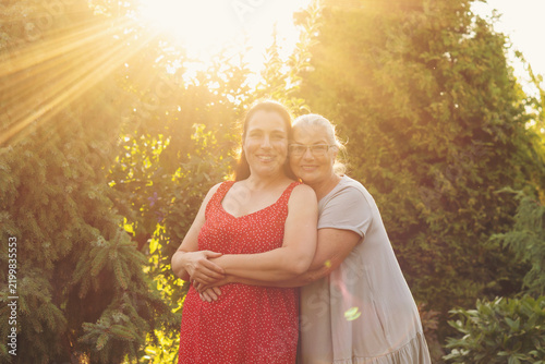 Adult Daughter Embracing Mother in Golden Garden Sunlight