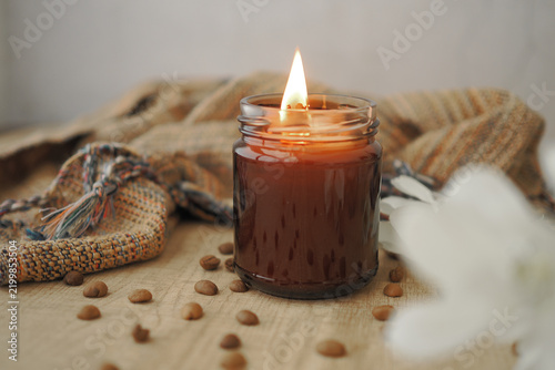 Foto Candle burning on a wooden table with coffee beans and a cloth nearby