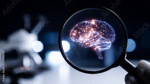 A magnifying glass reveals an illuminated human brain representing neurological research and medical analysis.
