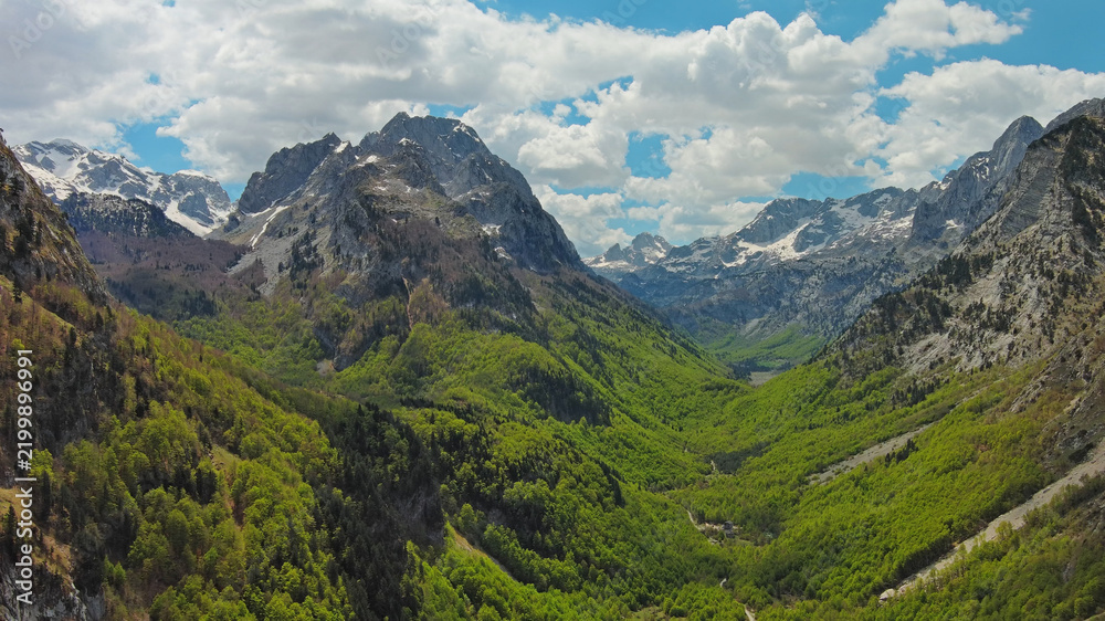 Obraz premium Rocky snow mountains and green valley aerial