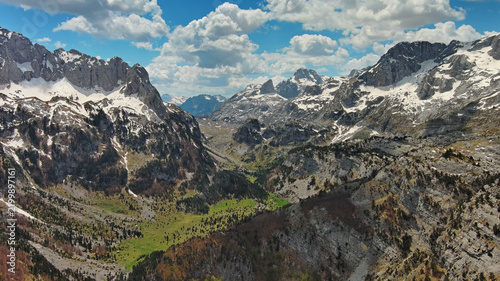 Rocky snow mountains and green valley aerial