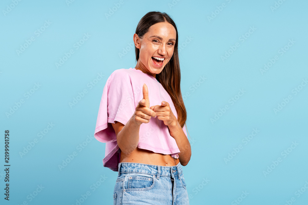 Fototapeta premium Happy young woman pointing fingers smiling at camera