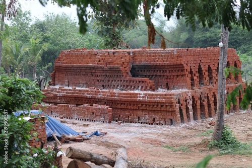 Traditional Red Brick Kiln with Stacked Clay Bricks in a Rural Village Setting.