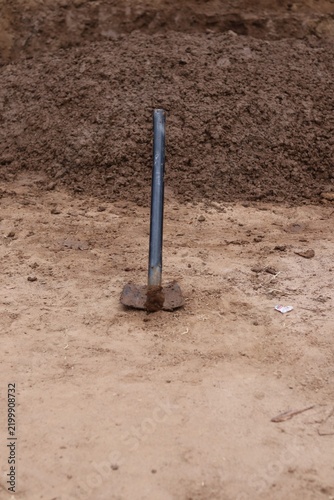 Traditional Agricultural Hoe Embedded in Dry Soil Near a Soil Mound for Farming and Land Preparation.