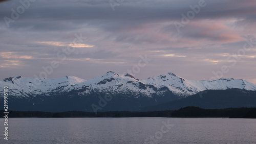 Breathtaking Alaska mountain glacier range view seen from outdoor deck of cruise ship liner sailing the Inside Passage transit with spectacular landscape scenery during sunset
