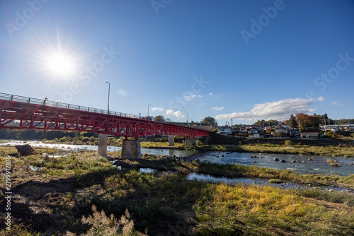Fototapeta 長野県佐久市を流れる千曲川と川面を渡る赤色が鮮やかな中津橋