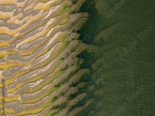 Cuadro en lienzo Natural textures of sand ripples and green vegetation meet the deep water in thi