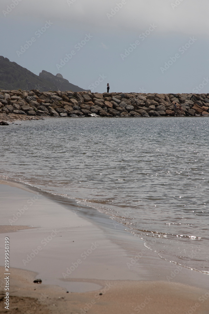 Fototapeta premium Person standing on rock jetty enjoying ocean view