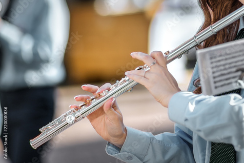 Close-up of a Woman Playing Silver Flute with Sheet Music Outdoors