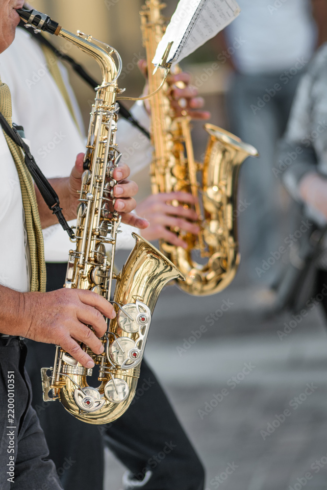 Fototapeta premium Close-up of Musicians Playing Saxophones Outdoors in Casual Setting