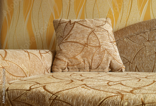 Close-up of beige upholstered sofa and decorative throw pillow featuring abstract geometric pattern. Concept of interior design, home comfort, furniture upholstery, textile patterns, living room decor