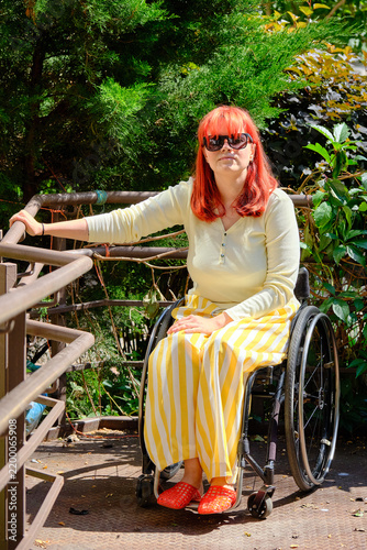 girl with bright red hair in yellow clothes posing while sitting in a wheelchair