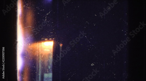 Dark vintage film texture with dust scratches and a warm glowing light leak on the left side