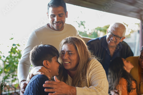 Multi generational latin american family having tender moment together at house patio - Grandmother hugging her grandson - Bonding, love and diverse age people concept