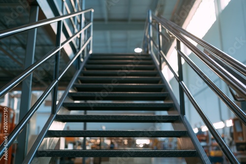 Steel stairs lead to upper level in industrial building with large windows
