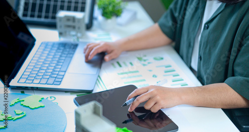 Fotografie Analyzing renewable energy and ESG data while utilizing computers and tablets to