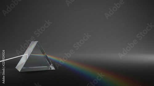 Transparent Triangular Prism Casting a Rainbow Across a Dark Surface