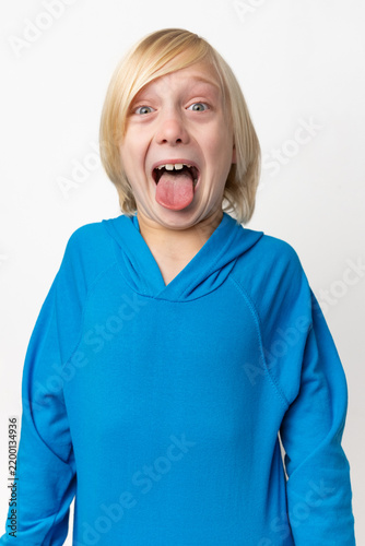Bild auf Leinwand Young blond child expressing a humorous emotion, widening eyes and sticking tong
