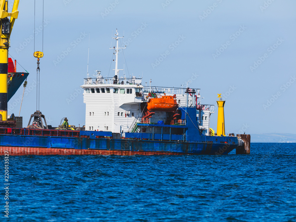 Fototapeta premium Commercial cargo ship unloading at a port