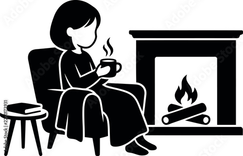 Cozy woman sitting in an armchair holding a warm cup of coffee near a fireplace