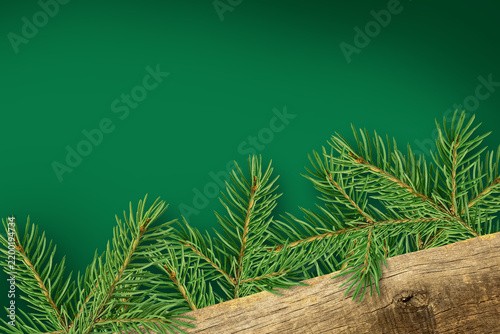 Pine branches laid out on a wooden board against a green background. Copy space.