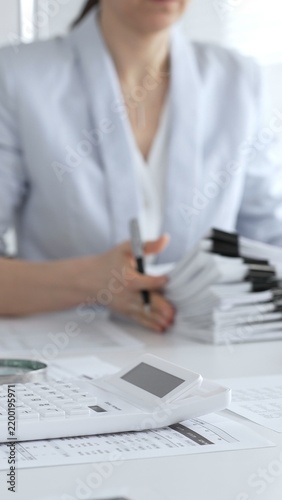 Business professionals collaborating at a desk, using a calculator and organizing financial documents for accounting, tax preparation, budgeting and corporate finance management. Audit and taxes