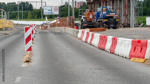 Roadwork in progress at a construction site with barriers on the side of the road in the middle of the day