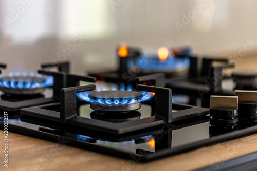 Gas cooktop with several blue flames. Kitchen appliance in use.
