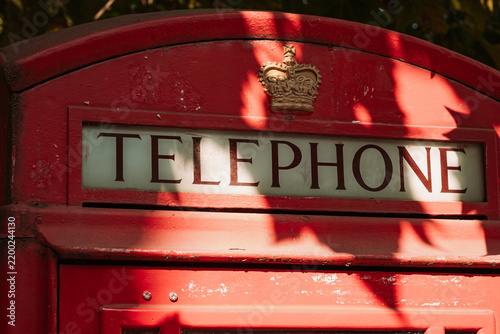 Close-up of iconic traditional British red telephone box upper frame showing royal crown emblem and telephone sign.