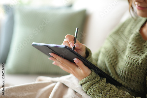 Woman hand handwriting on digital tablet in winter at home