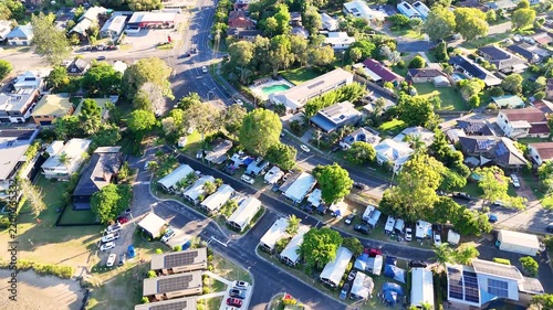 Aerial view of coastal holiday park with luxury cabins and caravan sites in sunny australian residential suburb at sunset.