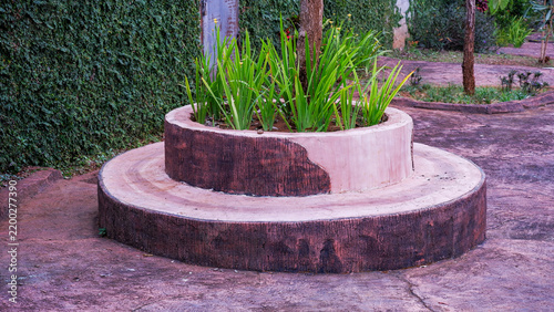 Foto Round concrete planter box with built-in ring seating painted in natural tree stump colors in a park