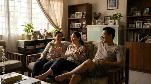 Happy adult siblings gathered in the cozy living room of their family home enjoying a joyful conversation and spending quality time together