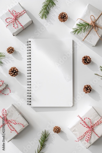 Wrapped Gifts and a Blank Notebook on a White Surface With Pinecones and Pine...