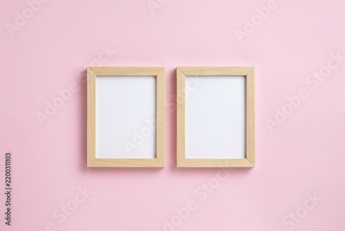 Two empty wooden frames side by side on a pastel pink background, empty frame blank