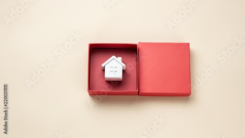 White house miniature inside open red gift box, down studio shot home model