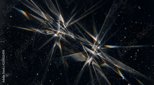 Geometric prism crystal light flare texture with rainbow chromatic aberration sharp triangular refraction rays and delicate dust speckles isolated on solid dark black backdrop overlay
