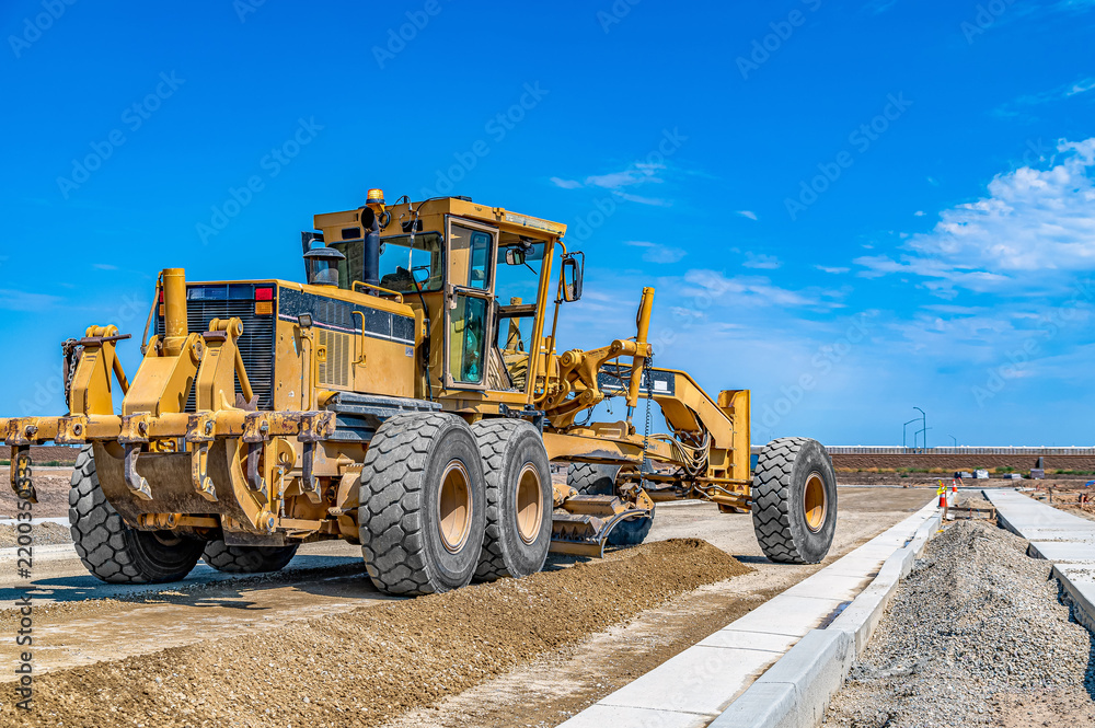 Fototapeta premium Motor grader prepares ground for roads and infrastructure in neighborhood. Construction, land development.