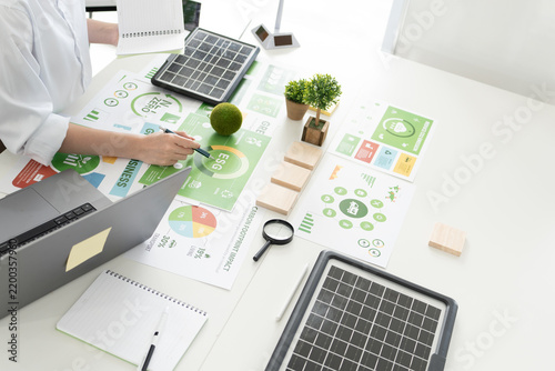 A diverse business team analyzing environmental charts and graphs in a collaborative meeting to create sustainable strategies in a modern office.