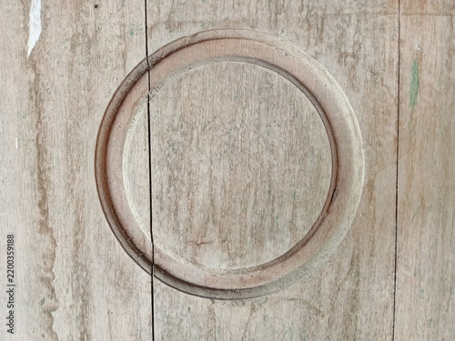 Close up of weathered rustic wooden surface with a carved circular pattern design