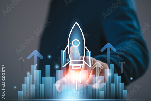 Startup growth concept showing a business professional launching a digital rocket above rising charts, symbolizing innovation, success, expansion, investment, strategy, future business opportunities.