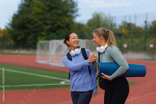 Diverse women friends smiling, connecting and walking together on a running track after a workout, sharing healthy lifestyle and wellness journey