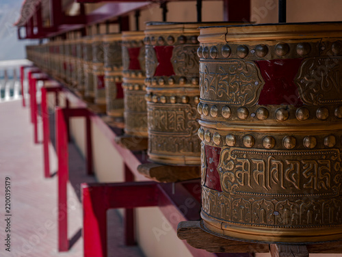 Fotografie Tibetan prayer wheel at Diskit Monastery in Ladakh, India, in sharp focus against a softly blurred background, highlighting intricate details and a peaceful Buddhist atmosphere