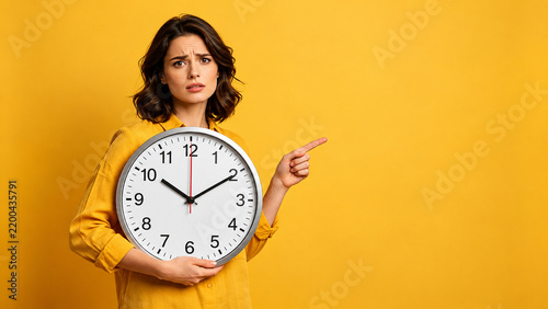 Woman Holding Clock and Pointing Against Yellow Background