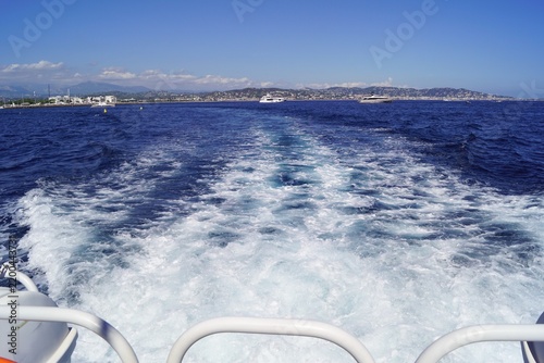 Boat wake on blue Mediterranean sea with coastal mountains