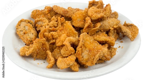 Crispy golden fried chicken skins served on a white plate against a clean isolated background