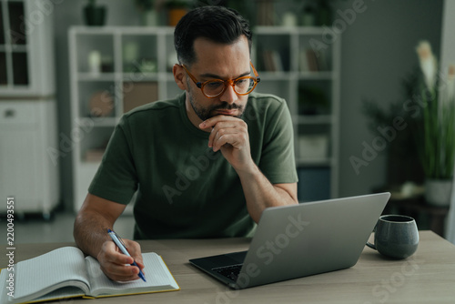 Man working from home using laptop and notebook